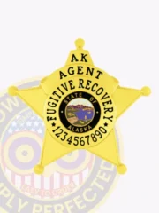Polished gold metal badge in the shape of a 5-point star for Alaska fugitive recovery agents, featuring black text "AK AGENT FUGITIVE RECOVERY" encircling the colorful state seal and a series of numbers at the bottom, equipped with a safety pin for easy wear.