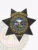 This image presents a sleek black custom metal badge for deputy sheriffs, centered on a bold 7-point star. The text "DEPUTY SHERIFF" arches above the badge, with "SOUTH DAKOTA" featured prominently in the center. Designed with a safety pin attachment, this badge combines functionality with authority.