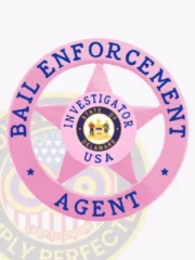 Bail enforcement agent badge in bright BCAM pink metal, featuring a five-point star inside a circle banner, labeled “BAIL ENFORCEMENT” on top and “AGENT” at the bottom, with “INVESTIGATOR USA” and the Delaware state seal in the center, secured by a safety pin.