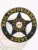 Circular black metal badge for bail enforcement agents, embossed with a five-point star and surrounded by a banner that reads “BAIL ENFORCEMENT AGENT,” including “OPERATIONS MANAGER” and the Delaware state seal in yellow text at the center, designed with a safety pin.