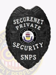 A sleek black shield-shaped badge adorned with rich textures and details. The phrase "SECURENET PRIVATE SECURITY" is displayed in bold white letters at the top, while a circular emblem containing "STATE OF COLORADO" captures attention at the center. The acronym "SNPS" is clearly printed below in contrasting white text. This custom metal badge for private security in black with safety pin attachment combines elegance with functionality for security professionals.