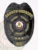 A polished black custom metal badge for deputy sheriffs features "DEPUTY SHERIFF" in prominent yellow lettering at the top. The central design includes a star containing the Colorado state seal, framed by "PINE VALLEY COUNTY" and "SHERIFF'S DEPT." Below, three stars add to the badge's elegance, while a safety pin attachment provides practicality for secure wearing.