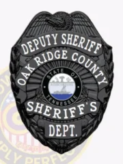 A polished black custom metal badge for deputy sheriffs features "DEPUTY SHERIFF" in clear lettering at the top. The central design includes an eagle motif above a circular emblem with the Tennessee state seal, along with "OAK RIDGE COUNTY SHERIFF'S DEPT." below. Enhanced by its safety pin attachment, this badge combines style and functionality.