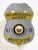 Bail enforcement agent badge in silver shield form with a raised silver eagle crest on top, gold lettering stating "Bail Enforcement Agent" and "Negotiator AZ," featuring the Arizona state seal in the center, flanked by blue letters "U" and "S," attached using a safety pin.