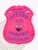 Bright pink metal badge with an eagle emblem crowning the shield, blue text including "POLICE OFFICER," the number "242" inside a central oval, the multicolor Michigan state seal between two deer, and a banner reading "100TH ANNIVERSARY VILLAGE OF HALFWAY," a custom BCAM pink eagle top metal badge with safety pin attachment.