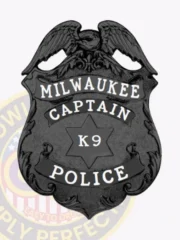 Black metal badge for Milwaukee Police Department K9 Captain showing a raised eagle at the top of the shield, white text on ribbons reading MILWAUKEE, CAPTAIN, and POLICE, and a star in the middle with K9 inscription, designed with a safety pin fastener.