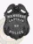 Black metal badge for Milwaukee Police Department K9 Captain showing a raised eagle at the top of the shield, white text on ribbons reading MILWAUKEE, CAPTAIN, and POLICE, and a star in the middle with K9 inscription, designed with a safety pin fastener.