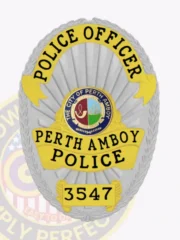 Custom silver oval metal badge for police officers in Perth Amboy, with bright yellow banners showing "POLICE OFFICER," "PERTH AMBOY POLICE," and badge number "3547" in black letters, encircling the colorful city seal of Perth Amboy on a silver textured background bordered by embossed leaves, designed with a safety pin on the back.