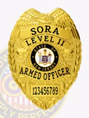 Detailed custom gold metal badge with an eagle design at the crest, black lettering reading SORA LEVEL II ARMED OFFICER, the New Jersey state seal in the middle, and a numeric ID plate 123456789, secured by a safety pin.