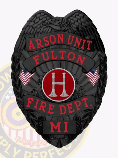 Matte black custom arson unit badge for Fulton fire department, eagle on top, red lettering on black ribbons with two American flags flanking a red circle containing a silver "H," designed with a safety pin closure.