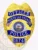 North Las Vegas Police officer badge made of gold metal with an eagle crest at the top, accented by blue reverse enamel banners stating Officer, North Las Vegas, Police, and badge number 1674, surrounding the official Nevada state seal, including a safety pin fastener.