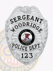 Silver metal badge designed for Woodridge Police Sergeant, showing an eagle crest at the top, black engraved text reading “SERGEANT WOODRIDGE POLICE DEPT.,” centered Illinois state seal, and number “123” at the base, attached by a safety pin.