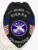 Matte black custom engineer badge for Sierra fire department, eagle on top, white lettering on black ribbons surrounding American flags and a navy circle with silver firefighting equipment in the center, designed with a safety pin closure.