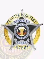 Detailed silver metal badge in the shape of a 5-point star with a gold banner behind, designed for Fugitive Recovery Agents. The badge includes the name Simon K., safety pin fastening, and a central seal showing the U.S. Bail Enforcement logo with stars and flags.