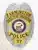 Silver custom metal badge with gold panels for Farmington Police Detective Inspector, decorated with an eagle symbol at the top, clear black embossed lettering "FARMINGTON DETECTIVE INSPECTOR POLICE 57," and a State of Maine insignia at center, attached using a safety pin.