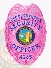 Bright pink metal badge designed for Loss Prevention Security Officers in California, showcasing a detailed eagle emblem on top, blue text, state seal in the middle, and a safety pin for secure fastening.