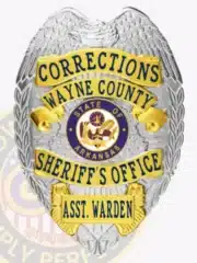 High-resolution image of a Wayne County Corrections assistant warden badge made of silver metal with gold-colored panels, featuring an eagle detail on top, blue lettering, and the State of Arkansas seal prominently in the center.