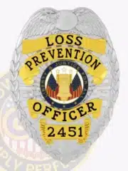 High-resolution photo of a silver metal badge for Lost Prevention officers, featuring an eagle at the crest, prominent gold panels with black engraved text "LOSS PREVENTION OFFICER 2451," and a central seal with patriotic symbols, equipped with a safety pin fastening.
