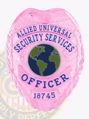 Close-up of a custom BCAM pink eagle top metal badge for Allied Universal showing the detailed embossed eagle at the top, surrounded by laurel leaves, with "Allied Universal Security Services Officer" text in bold blue letters and a safety pin attachment on the back.