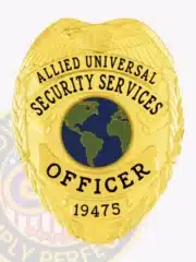 Front view of an Allied Universal custom gold metal officer badge featuring an embossed eagle at the top, a globe graphic in the center, bold black text stating "Security Services Officer," and a visible safety pin attachment for practical use.