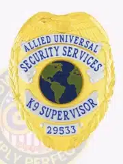 Detailed custom Allied Universal K9 Supervisor badge featuring a gold eagle at the top, silver text panels with blue lettering, a globe emblem in the center, and a safety pin fastener.
