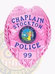 Bright pink Police Chaplain badge for Stockton, California, designed with a pink eagle atop, matching pink background, blue text surrounding the California state seal, and badge number "99," equipped with a safety pin for secure fastening.
