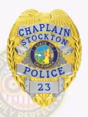Detailed image of a custom metal badge for Stockton Police Chaplain, combining a gold eagle top with silver accent panels, including the text "CHAPLAIN STOCKTON POLICE," the official California state seal, and badge number "23," with a safety pin on the back.