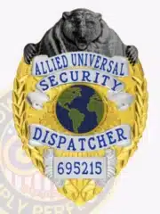 Close-up of custom gold and silver metal badge for Allied Universal Security Dispatcher, showcasing a black bear top design, silver panels with blue text, and badge number 695215 with safety pin fastener.