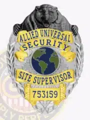 Detailed Allied Universal Site Supervisor badge featuring a silver metal base with gold panels, blue lettering, a black bear sculpted on top, and a globe emblem in the center, secured by a safety pin.