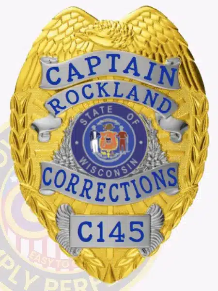 Custom-designed gold metal badge with an eagle at the top, highlighted by silver panels displaying "Captain Rockland Corrections" in blue text, the official Wisconsin state seal in the center, and badge number C145, equipped with a safety pin for attachment.