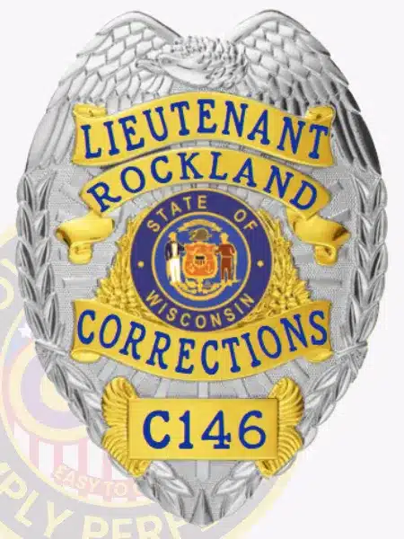 Detailed photo of a silver and gold law enforcement badge for Rockland Corrections, showing an eagle crest on top, gold banners with blue lettering for "Lieutenant Rockland Corrections," the Wisconsin state emblem in the center, and badge number C146 at the bottom.