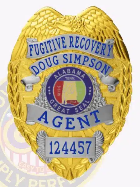 Gold eagle-top badge with silver decorative panels for Fugitive Recovery Agent Doug Simpson, displaying the Alabama state seal in the center, bold blue text for name and title, unique number 124457 at the bottom, and a safety pin fastener.