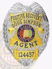 Silver eagle-top badge with gold decorative panels for Fugitive Recovery Agent Doug Simpson, displaying the Alabama state seal in the center, bold blue text for name and title, unique number 124457 at the bottom, and a safety pin fastener.