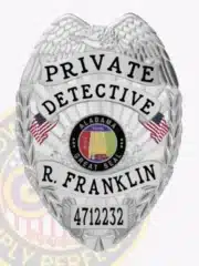 Custom silver police detective badge for Alabama private detective R. Franklin, decorated with an eagle symbol at the top, black embossed lettering "PRIVATE DETECTIVE," the Alabama Great Seal in the center, two American flags on each side, and a safety pin for secure attachment.
