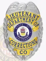 Detailed custom badge showing a silver eagle on top, gold-colored panels with blue text reading "Lieutenant Department of Corrections," and a circular Colorado state emblem at the center. The badge has a safety pin attachment for secure wear.
