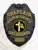 Custom black metal badge for Community Care Responder Chaplain, featuring an intricate eagle design at the top, bright yellow lettering around a circular emblem of a cross and waving American flag, and a safety pin attachment for easy fastening.