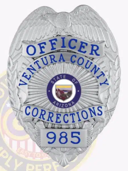 Silver custom corrections badge for Ventura County Officer with an eagle figure at the top, blue lettering on silver panels, central Arizona state seal, badge number 985, and safety pin backing.