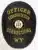 Oval-shaped black metal badge with gold letters reading "Officer Rehabilitation Corrections WY." The center displays the official Wyoming state seal, and the badge is equipped with a safety pin for secure attachment.