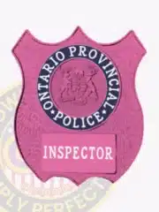Bright pink BCAM custom metal shield badge for Ontario Provincial Police inspectors, showcasing detailed provincial emblem and clear white 'INSPECTOR' label, equipped with a safety pin on the back.
