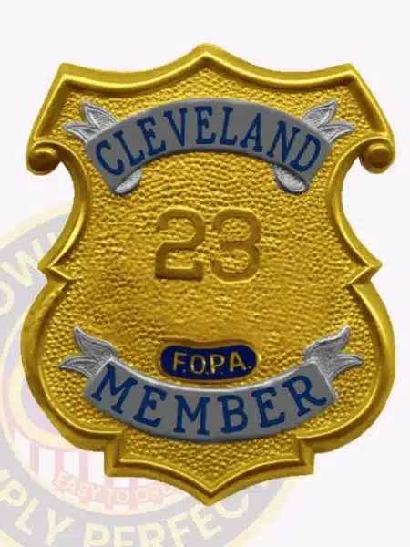 Image showing a custom gold shield metal badge with silver panels for Fraternal Order of Police Cleveland member, highlighting the detailed textured gold surface, silver banners with blue text, prominent number "23," and a safety pin backing for secure wear.