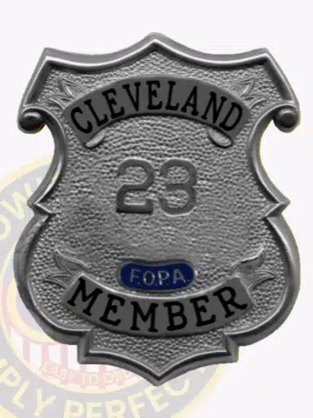 Detailed photo of a custom silver shield metal badge for Fraternal Order of Police Cleveland member, highlighting the rugged textured silver metal surface, raised number 23, prominent black lettering, and practical safety pin backing for easy wear.