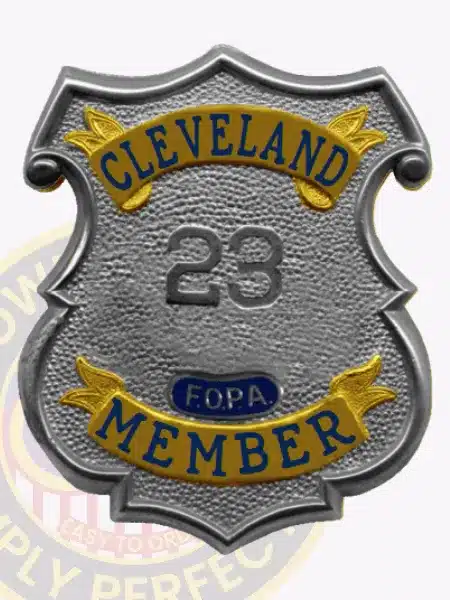 Detailed image of a custom silver shield metal badge designed for the Fraternal Order of Police Cleveland member, showcasing smooth silver edges, gold decorative panels with embossed lettering, and a safety pin attachment on the back for easy mounting.