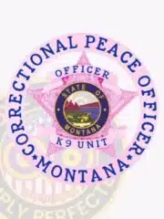 Custom BCAM pink 5-point star metal badge with an outer circular banner for Montana Correctional Peace Officers, featuring intricate embossed detailing on the star, a central seal displaying the "STATE OF MONTANA" emblem with mountains and wildlife, surrounded by blue text "CORRECTIONAL PEACE OFFICER MONTANA," and banners reading "OFFICER" and "K9 UNIT"; includes a safety pin attachment.