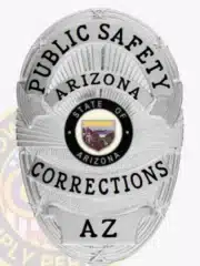 Matte silver custom BCAM corrections badge for Arizona public safety personnel, oval design with bold black lettering and official Arizona state seal in the center, equipped with a safety pin attachment.