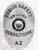 Matte silver custom BCAM corrections badge for Arizona public safety personnel, oval design with bold black lettering and official Arizona state seal in the center, equipped with a safety pin attachment.
